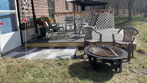 A wooden deck with outdoor furniture, a fire pit, and a patio umbrella. - Light and Airey new apartment on Apple Orchard minutes from Sylvan Beach (Blossvale)
