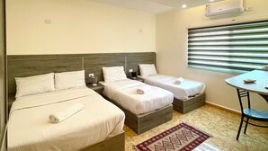 A hotel room with two beds, a small table, and a window with blinds. - RoadHouse (Wadi Musa)