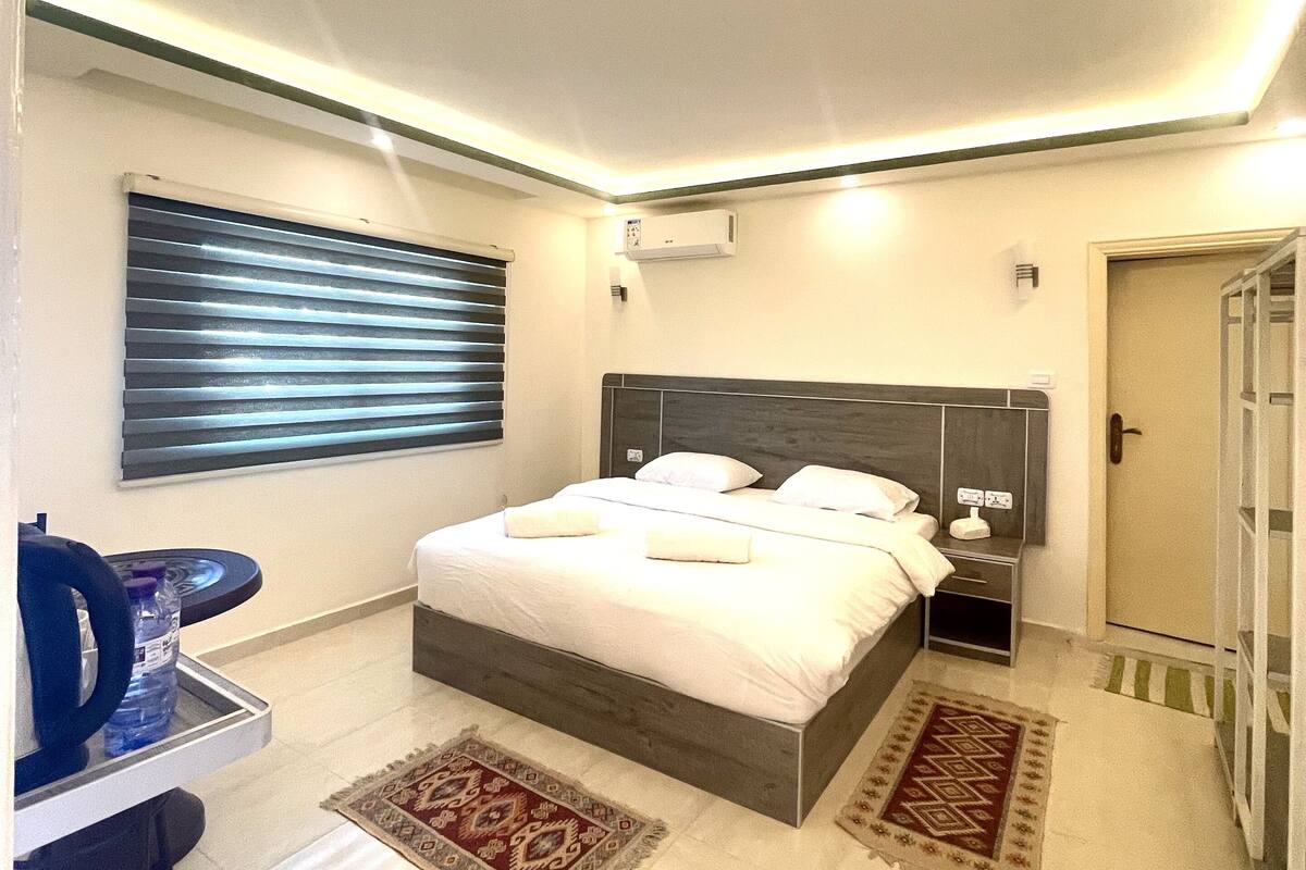 Quarto moderno com cama, mesas de cabeceira, escrivaninha e cadeira.