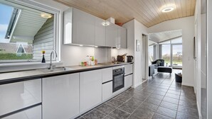 A modern kitchen with a large island, stainless steel appliances, and a view to the outdoors.