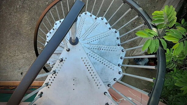 Una escalera en espiral con barandillas de metal y un poste central.