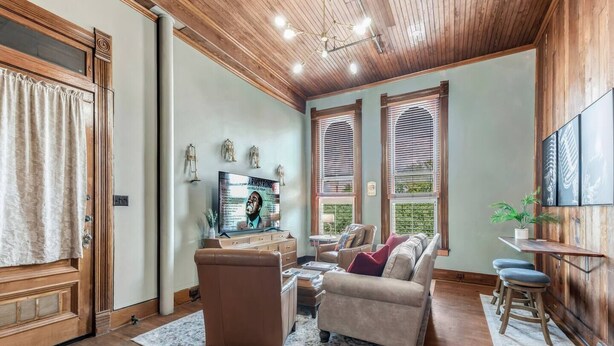 A cozy living room with a fireplace, a television, and comfortable seating. - Satchmo: Dwntwn Bryan-Main Street, 2nd floor, King Beds (Bryan)