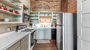 A compact kitchen with a gas stove, oven, and stainless steel refrigerator. - Satchmo: Dwntwn Bryan-Main Street, 2nd floor, King Beds (Bryan)