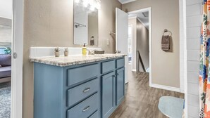 A bathroom with a large vanity, a mirror with lights, a towel rack, and a shower area. - St Simons: 3 Bedroom, Walk to A&M, King Beds (Bryan)