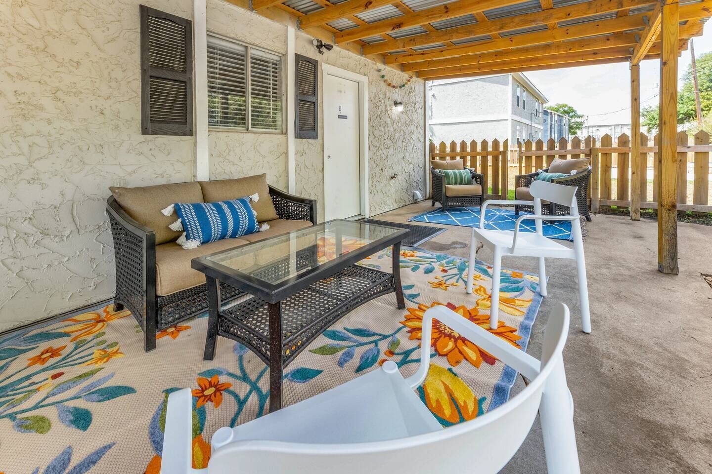 An outdoor patio with a glass-top table, two sofas, and a wooden deck.