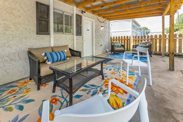 An outdoor patio with a glass-top table, two sofas, and a wooden deck. - St Simons: 3 Bedroom, Walk to A&M, King Beds (Bryan)