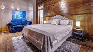 A bedroom with a large bed, a blue sofa, a floor lamp, and a painting on the wall. - Starry Night: Dwntwn Bryan on Main St, 2nd Flr, King Bed (Bryan)