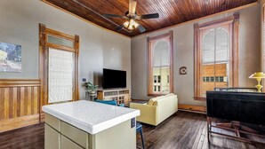 A living room with a wooden ceiling, a television, a sofa, and a dining table. - Starry Night: Dwntwn Bryan on Main St, 2nd Flr, King Bed (Bryan)