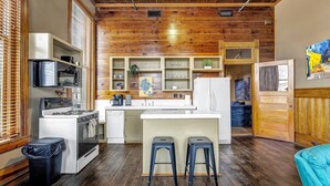 A compact kitchen with wooden ceiling, white cabinetry, and a central island with stools. - Starry Night: Dwntwn Bryan on Main St, 2nd Flr, King Bed (Bryan)