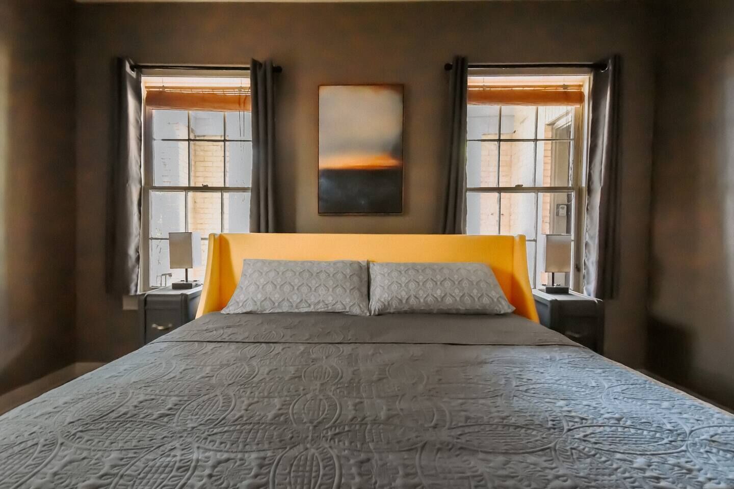 Une chambre à coucher avec un grand lit, deux tables de chevet et une fenêtre avec des rideaux.