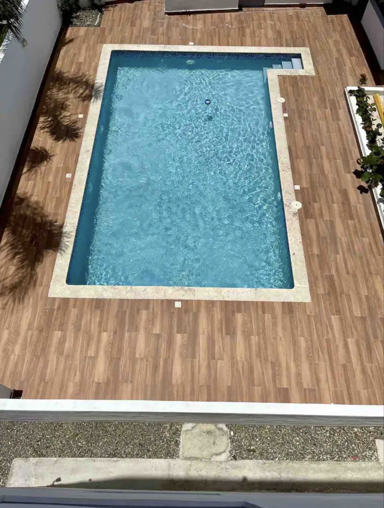 A rectangular swimming pool with a wooden deck surrounding it.