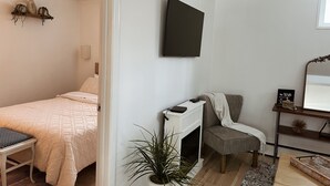 A bedroom with a bed, bedside table, and a TV mounted on the wall.