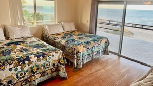 A room with two beds, a ceiling fan, and a large window with a view of the ocean. - Beachfront House on Beautiful Laguna Percebu Beach (San Felipe)