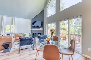 A modern living room with a sofa, chairs, a fireplace, and a large sliding glass door to a deck.