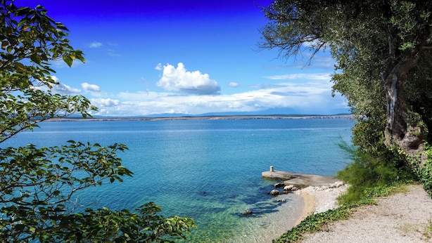 A coastal landscape with clear blue water, a rocky shoreline, and a path leading to the beach. - Holiday apartment with a balcony and sea view (Dramalj)