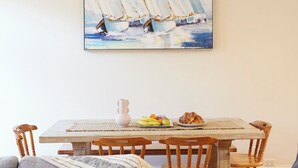 Ein Esstisch mit Untersetzer, einer Vase und einer Schale mit Früchten und Croissants.