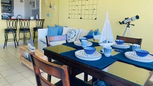 A dining area with a table set for four, chairs, a ceiling fan, and a telescope on a tripod.