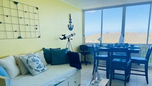 A room with a bed, a desk, and a view of the beach.