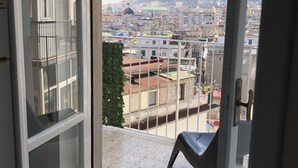Uma varanda com vista para uma paisagem urbana, incluindo edifícios e uma colina ao longe.