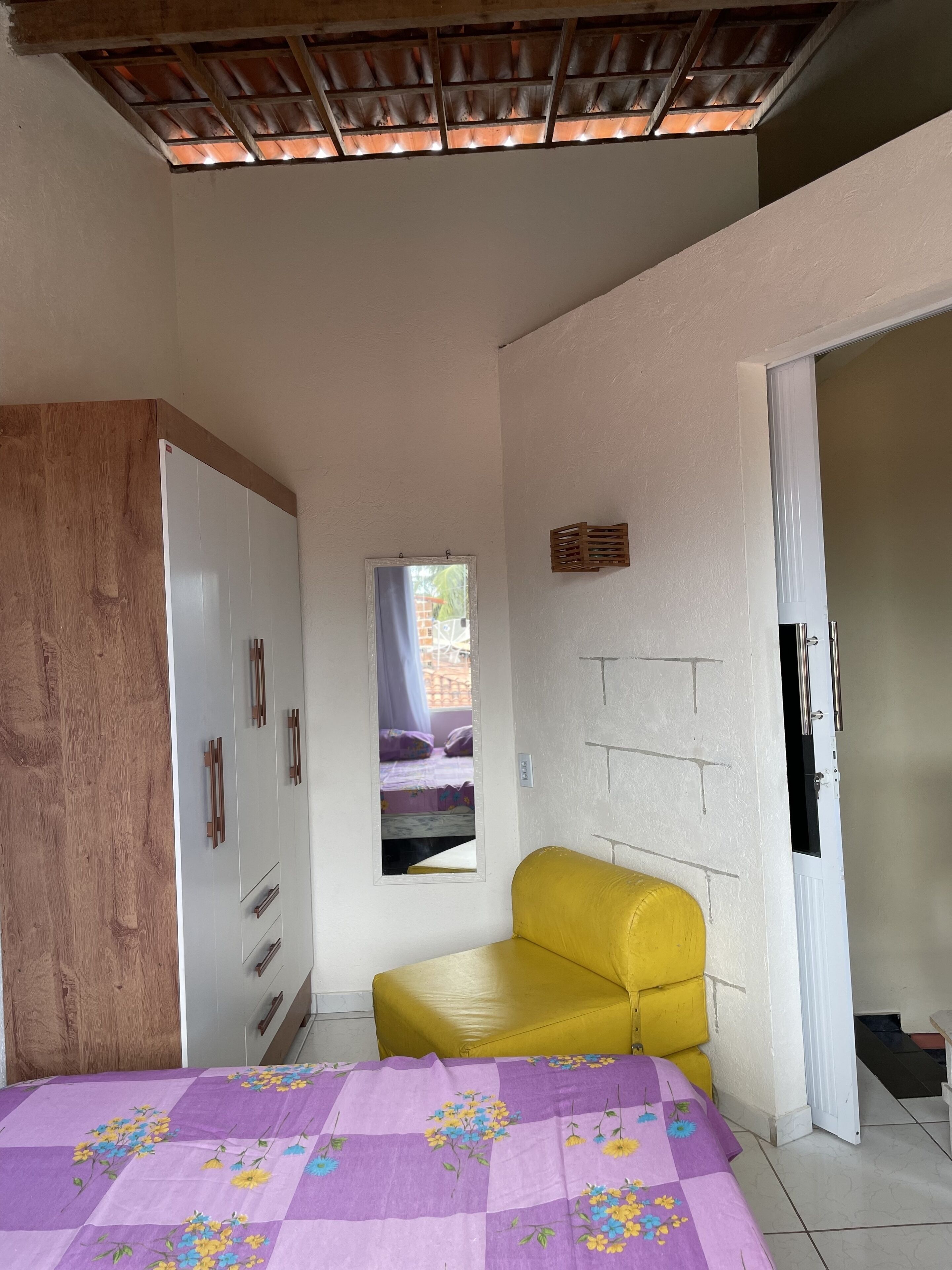 A bedroom with a bed, a wardrobe, a mirror, and a window.