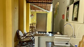 Une cuisine compacte avec un carrelage au sol, un évier et un petit coin repas avec des chaises.