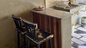 Une cuisine avec un dosseret carrelé, un évier et un coin bar équipé de deux chaises.