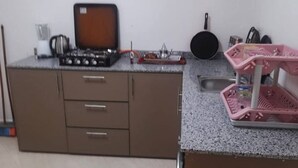 Una cocina con estufa a gas, un lavamanos y un escurreplatos rosa.