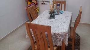 Comedor con una mesa cubierta por un mantel de encaje, rodeado de sillas de madera.