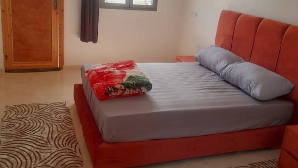 Un dormitorio con cama, puerta de madera y ventana con cortinas.