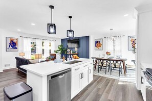 A modern kitchen with a central island, built-in dishwasher, and pendant lighting. - Moderne Luxe Home | Mins to ATL & Decatur Sq (Decatur)