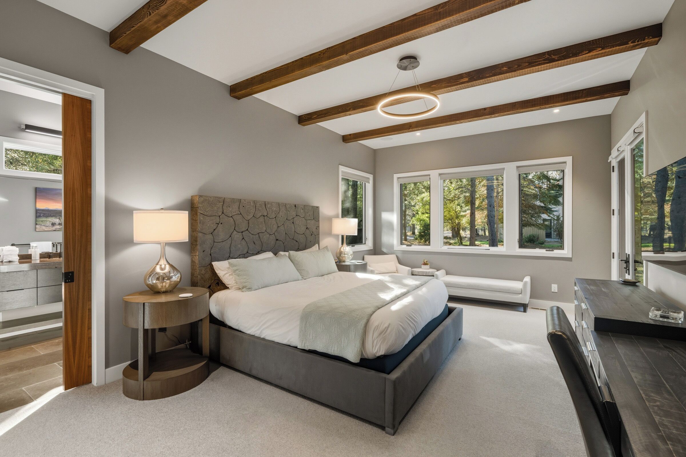 Een moderne slaapkamer met een groot bed, houten balken en een stenen hoofdeinde.