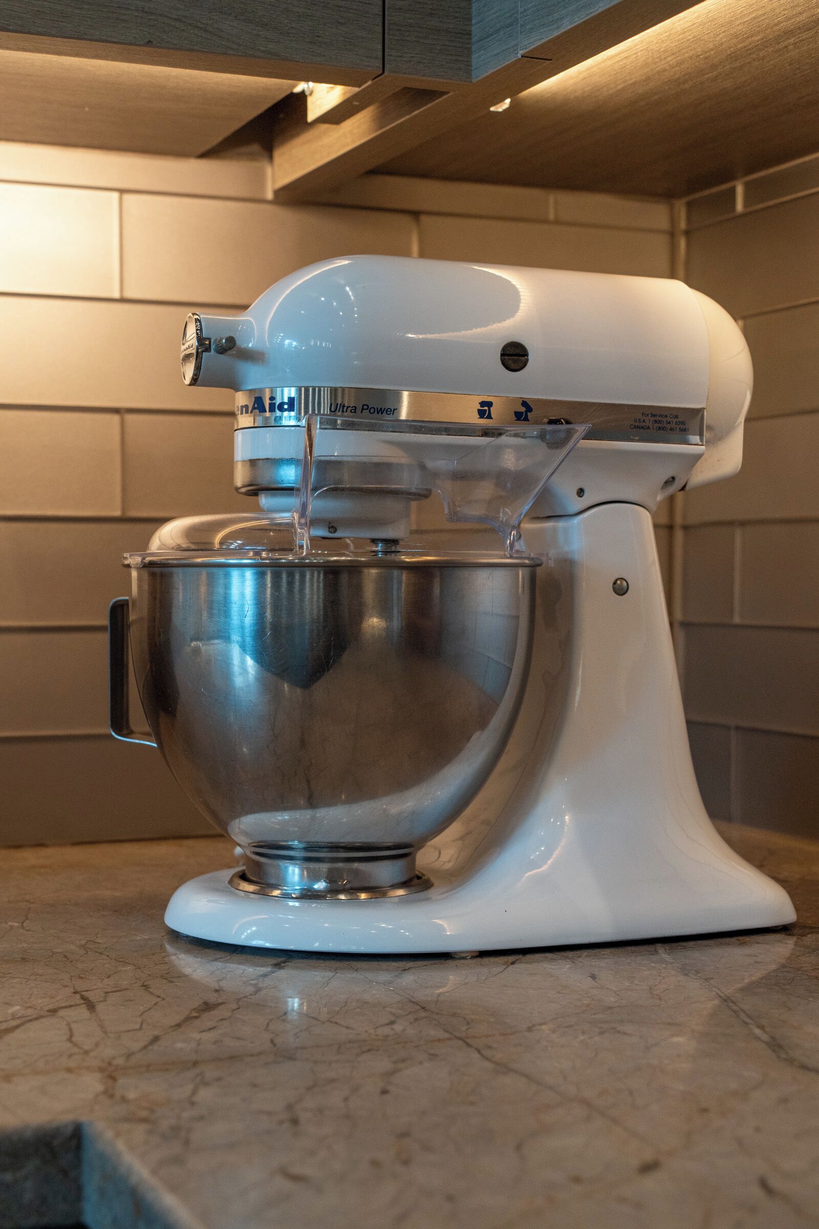 Une cuisine avec un robot pâtissier blanc posé sur un plan de travail en marbre.