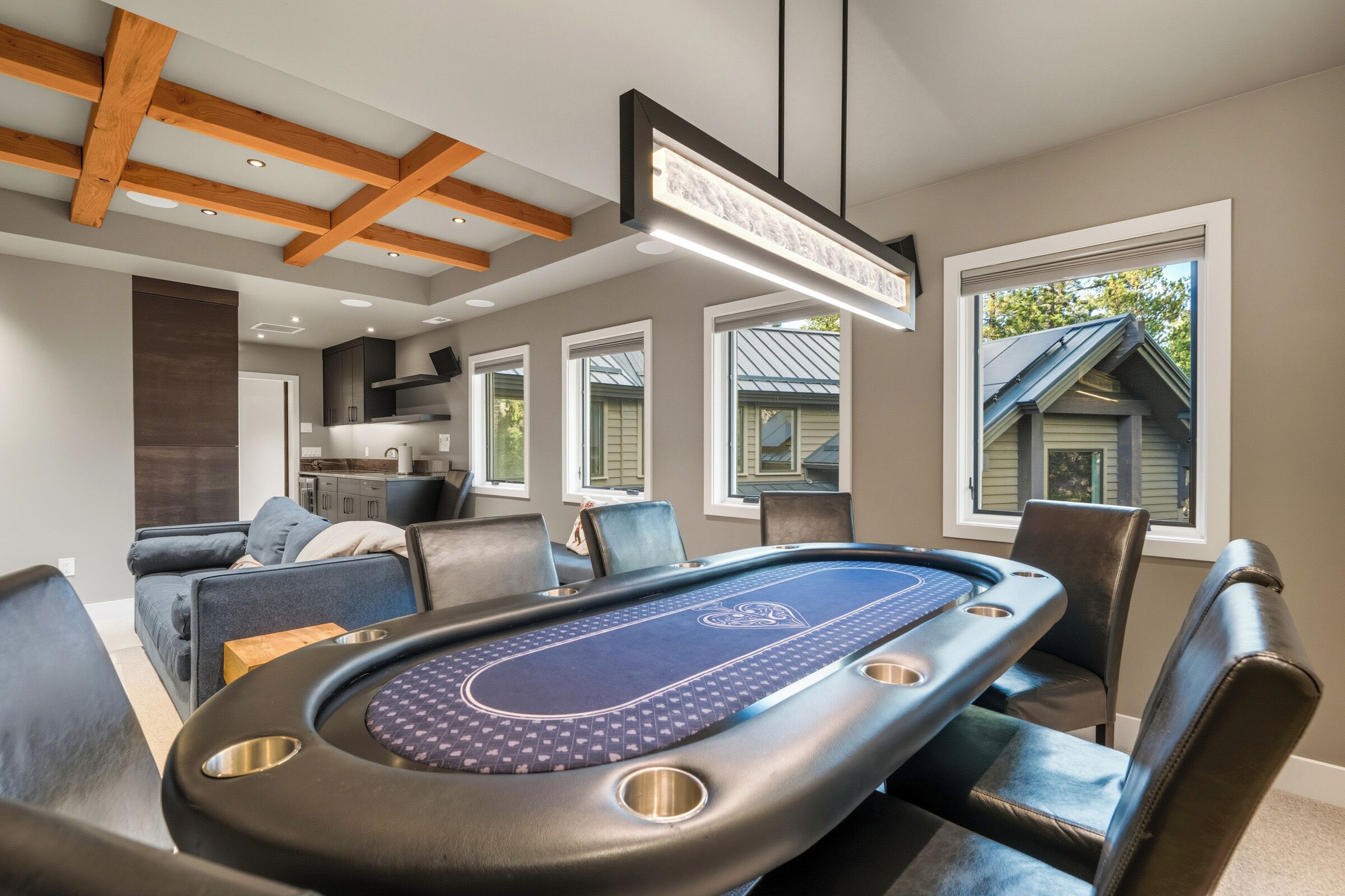 A pool table in a room with a modern design, featuring a ceiling with exposed beams and a large window.