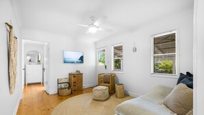 A spacious living room with a large round rug, a sofa, a wooden cabinet, and a wicker chair. - Driftwood Mudjimba-Beach Holiday (Sunshine Coast)