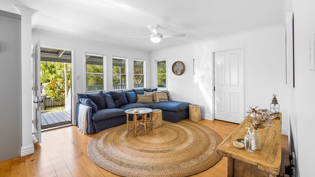 A spacious living room with a blue sofa, a round woven rug, and a wooden coffee table. - Driftwood Mudjimba-Beach Holiday (Sunshine Coast)