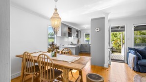 A modern kitchen with grey cabinets, a wooden dining table, and a hanging light fixture. - Driftwood Mudjimba-Beach Holiday (Sunshine Coast)