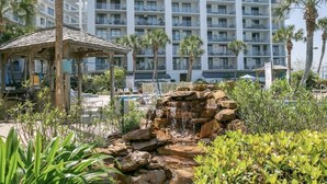 A hotel with a pool, a waterfall feature, and palm trees.