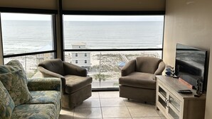 A living room with a large window, two sofas, a TV, and a cabinet.