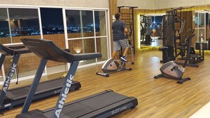 Un gimnasio con cintas de correr, una bicicleta estática y máquinas de pesas.