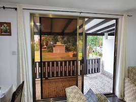 A room with a sliding glass door leading to an outdoor area with a patio, a small table, and a chair.