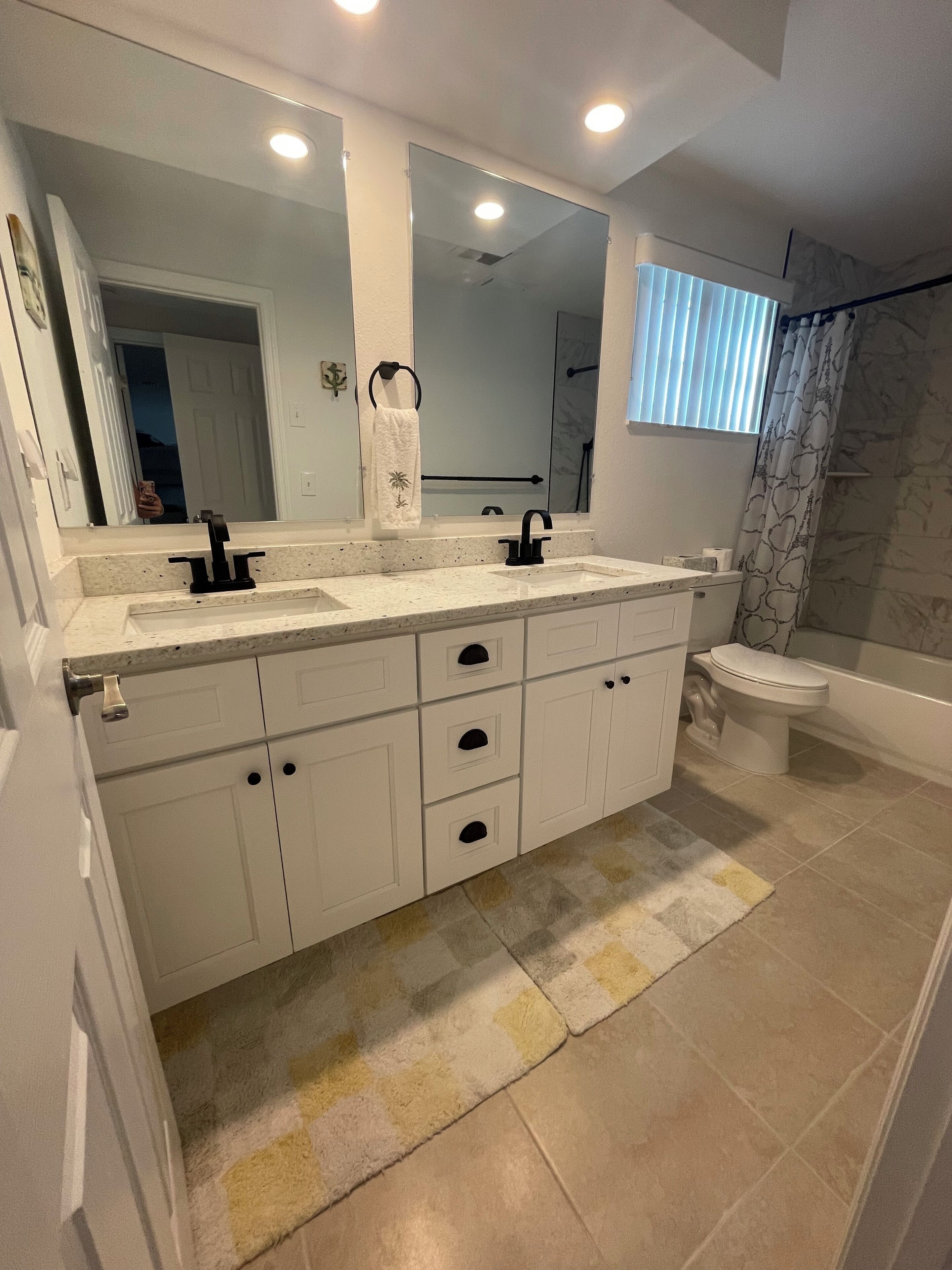 A modern bathroom with a double sink vanity, a toilet, and a shower area.