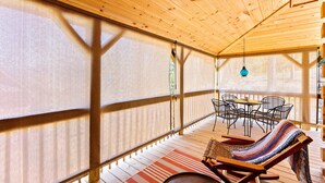 Una terraza de madera con un área de estar cubierta, una mesa y sillas.