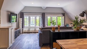 Una cocina moderna con horno empotrado, una mesa de comedor y un amplio ventanal con cortinas.