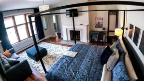 Un dormitorio moderno con una cama grande, un escritorio y una chimenea.