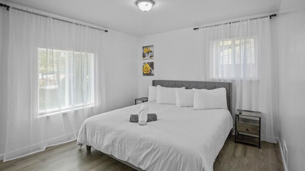 Ein Schlafzimmer mit einem großen Bett, weißen Vorhängen und einem kleinen Nachttisch.