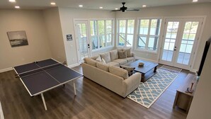 A spacious living room with a ping pong table, a beige sofa, and a coffee table.