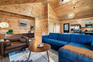A cozy cabin interior with a living room, sofa, coffee table, and kitchen area. - *Pet Friendly *MtnViews *HotTub*Game Room*Fire pit (Sevierville)