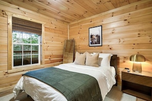 A wooden-paneled bedroom with a bed, pillows, a nightstand, and a window. - *Pet Friendly *MtnViews *HotTub*Game Room*Fire pit (Sevierville)