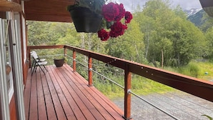 En træterrasse med gelænder, en hængende blomsterpotte med røde blomster, og et skilt med teksten "WEST SIDE STORY".