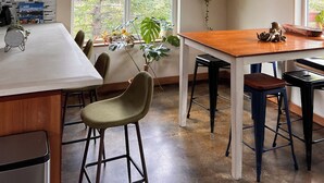Et køkken med træloft, spisebord, stole og en hængende lampeskærm.